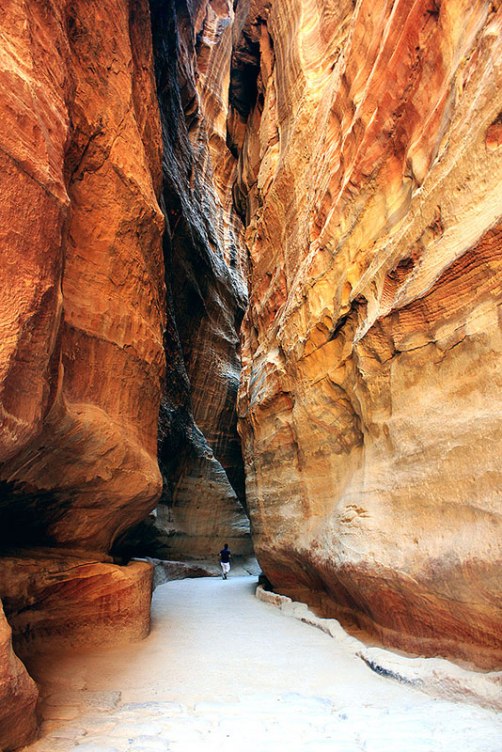 Photograph of a man walking in-between the stunning rock formations around the ancient Nabataean city of Petra, Jordan